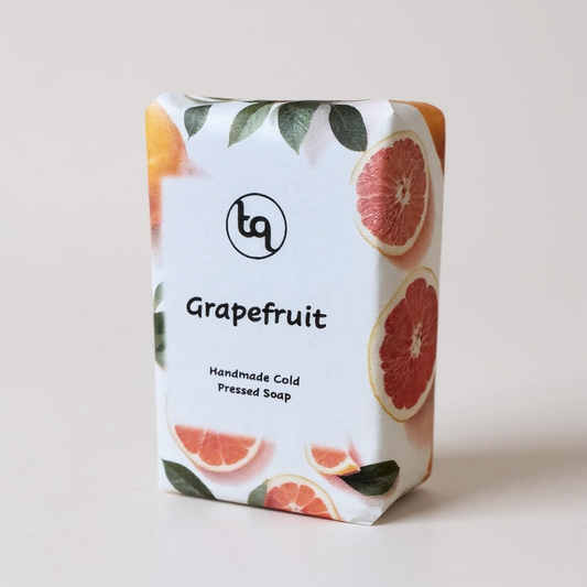 Grapefruit soap bar with packaging featuring grapefruit slices and leaves on a light background