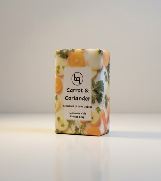 The main product photograph of a Truequest carrot and coriander cold-pressed soap bar, fully enclosed in its clean paper wrapper with the main retail label facing forwa