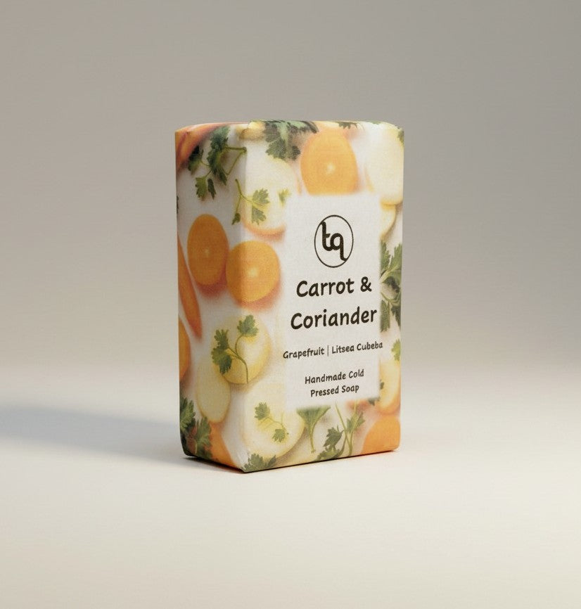 A front-facing main product shot of a single Truequest carrot and coriander cold-pressed soap bar. The rectangular bar is neatly wrapped in protective retail paper packaging, with the front label prominently displaying the Truequest brand name, carrot and coriander scent, and product logo against a clean background.