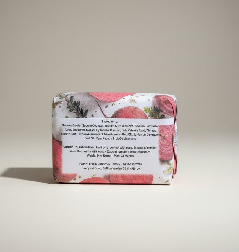 The back view of a paper-wrapped Truequest beetroot and thyme cold-pressed soap bar, clearly displaying the printed ingredients list and product details.