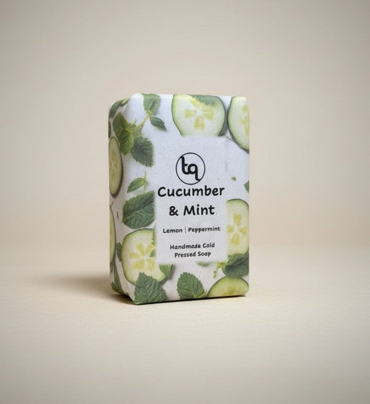 A direct front view of a Truequest cucumber and mint cold-pressed soap bar, neatly enclosed in its paper packaging wrapper with the main product label facing forward