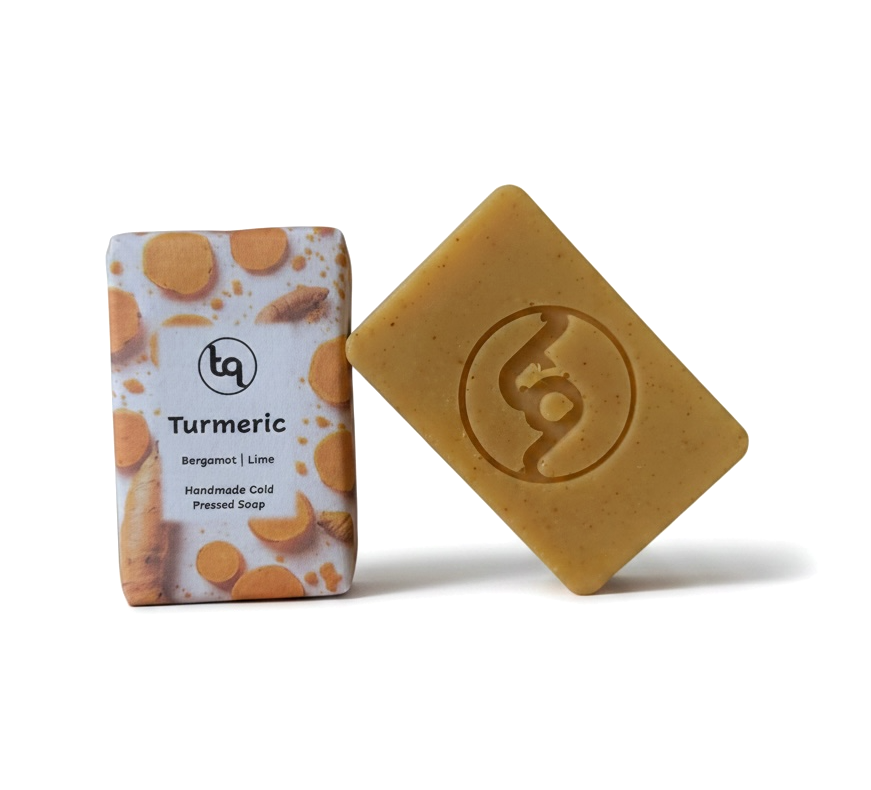 A product photo of two Truequest turmeric cold-pressed soap bars, featuring one bar neatly enclosed in its paper packaging and a second unwrapped bar resting at a dynamic angle to showcase its rich golden colour