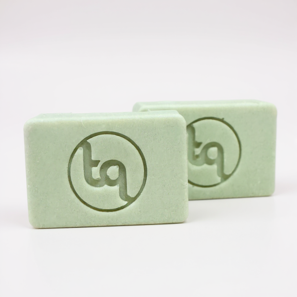 Two green soap bars with Truequest logo on a white background