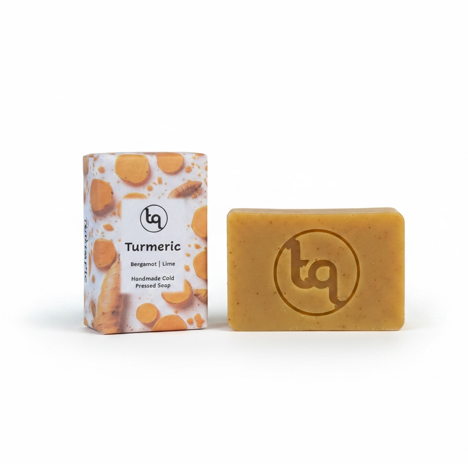A product photo of two Truequest turmeric cold-pressed soap bars, featuring one bar neatly enclosed in its paper packaging and a second unwrapped bar