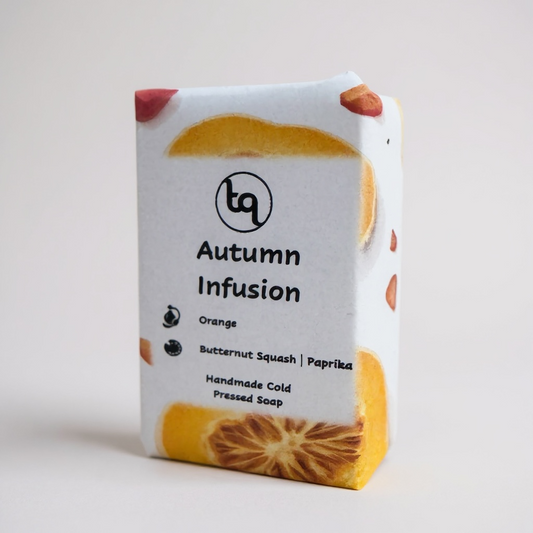Soap bar with 'Autumn Infusion' packaging featuring slices of butternut squash, paprika and orange essential oil on a light gray background