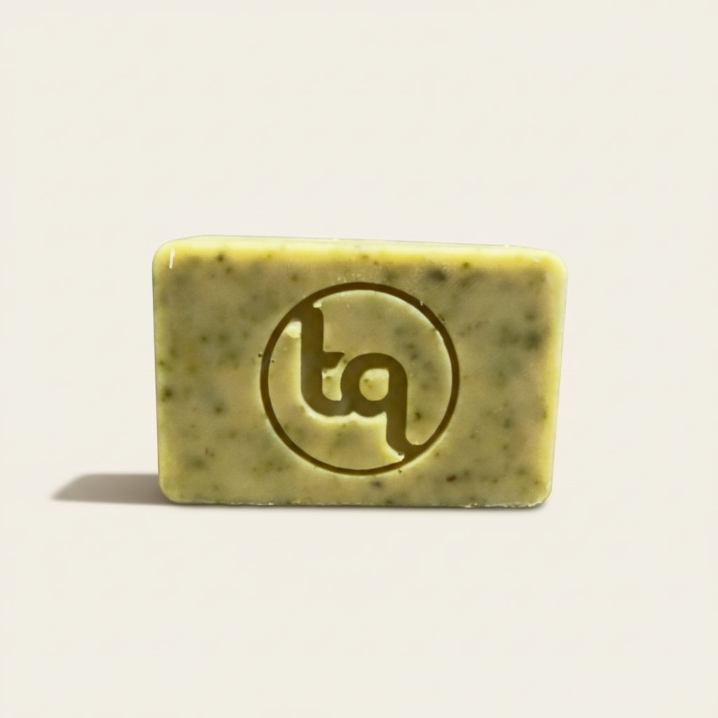 Naked bar of Truequest carrot, coriander and swede 'Sweet Earth' soap packaging with a bar of soap and slices of carrot and coriander leaves on a beige background