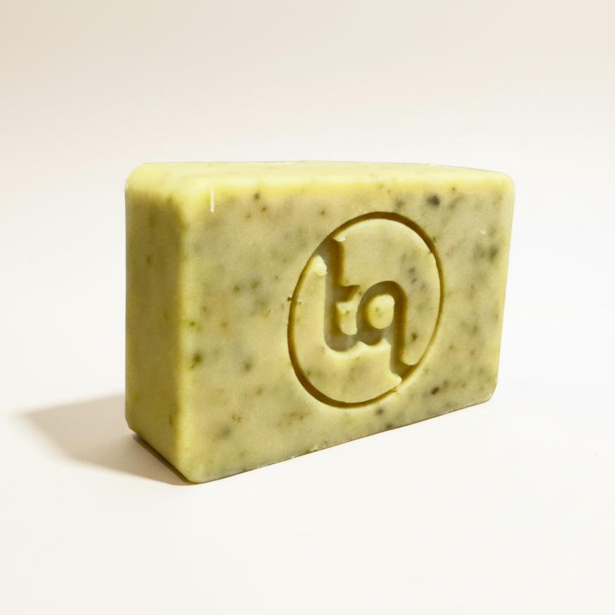 Bar of carrot and coriander soap scented with litsea cubeba and grapefruit essential oils with Truequest logo on a white background
