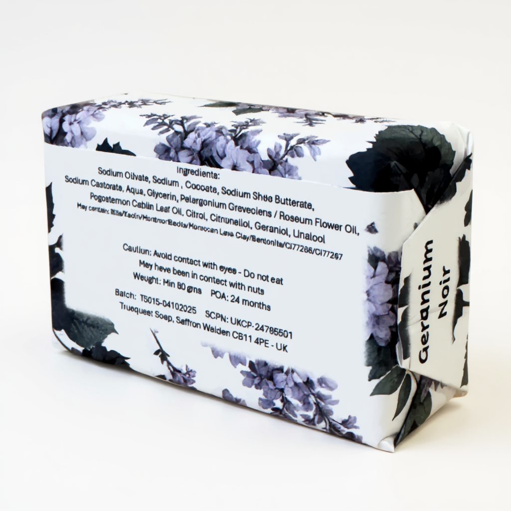 Truequest Geranium Noir soap wrapped in white paper with black and purple floral illustrations, showing the full ingredient list on the back.