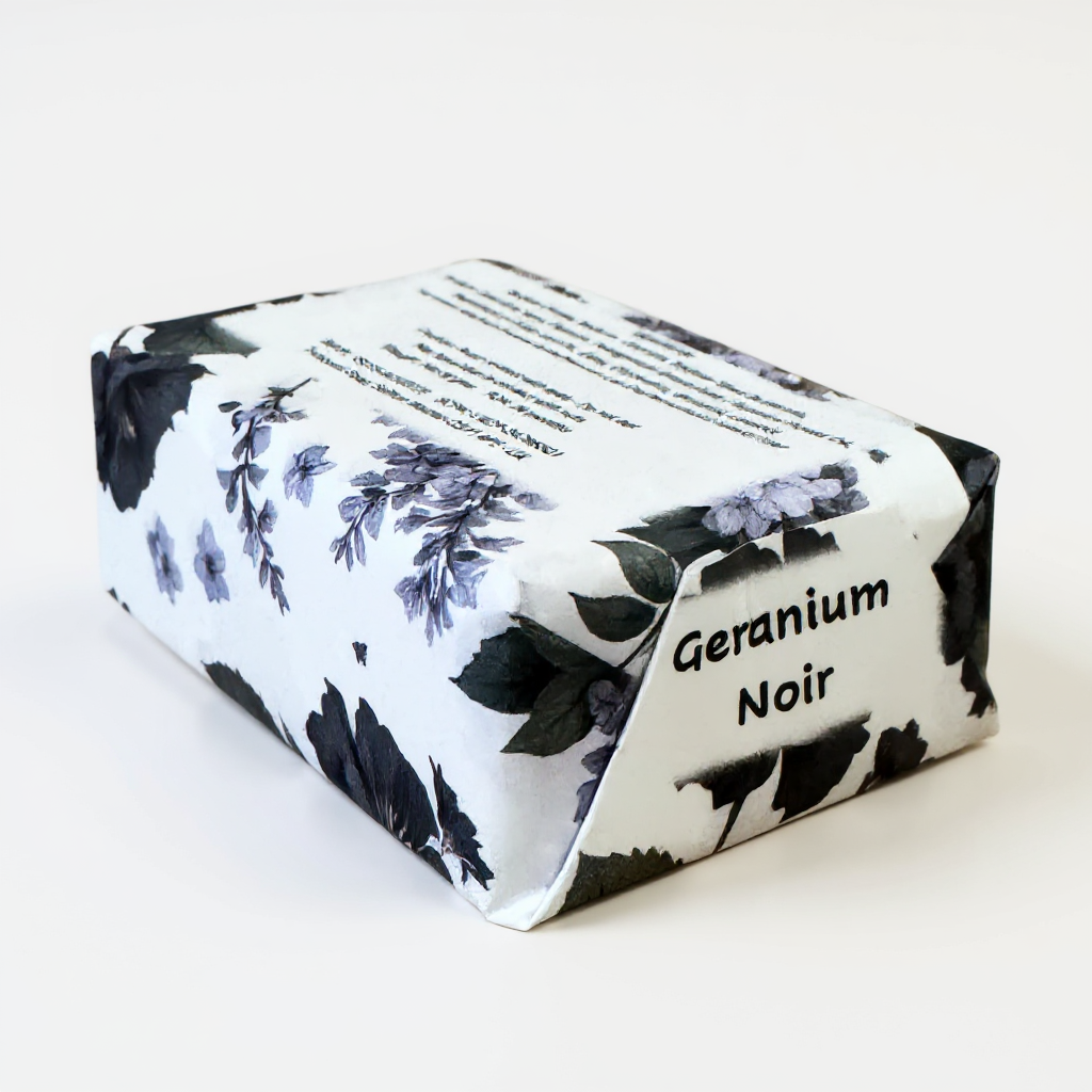 Truequest Geranium Noir soap wrapped in white paper with black and purple floral illustrations.