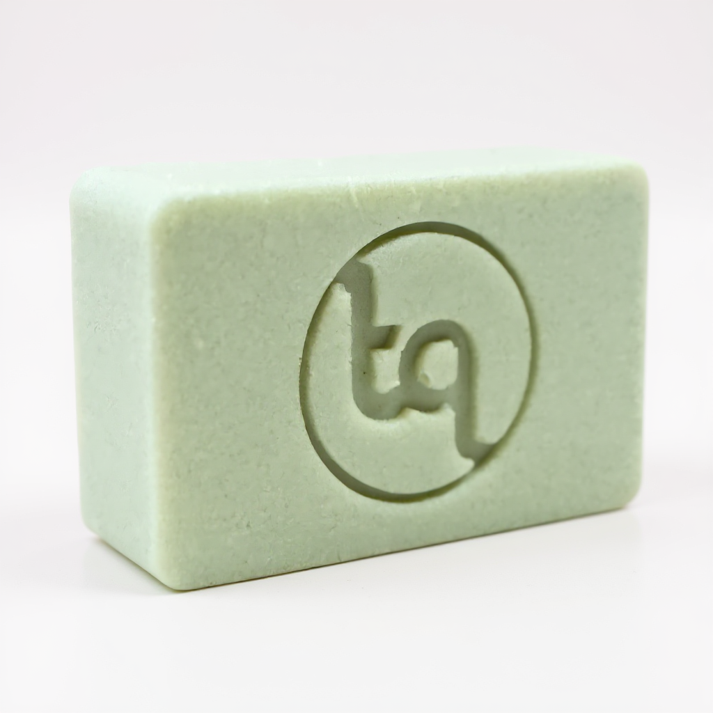 Light green Truequest soap bar with an engraved circular tq logo on the surface.