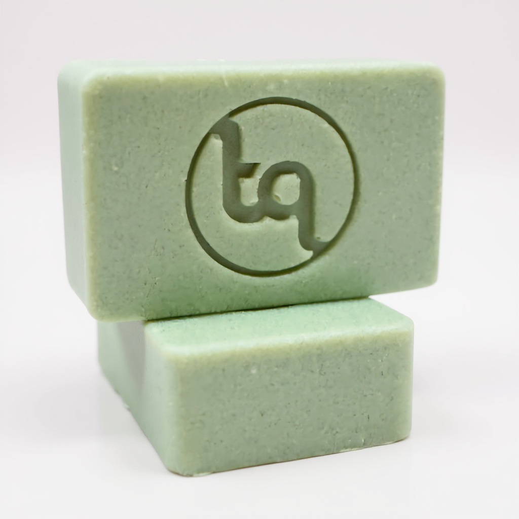 Two stacked Truequest Herbal Drift green cold pressed soap bars with an embossed circular logo on the top bar.