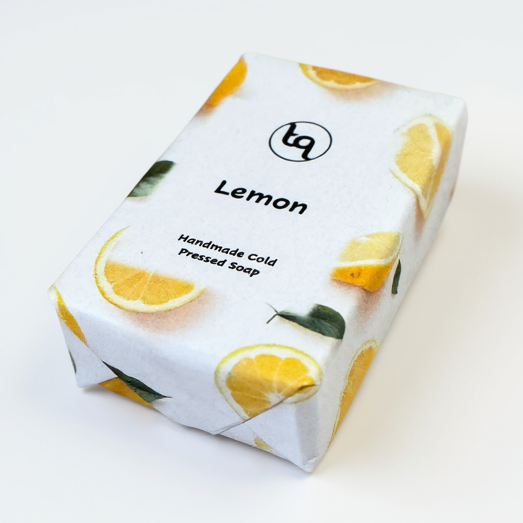 Truequest lemon handmade soap wrapped in white paper decorated with yellow citrus slices and leafy accents.