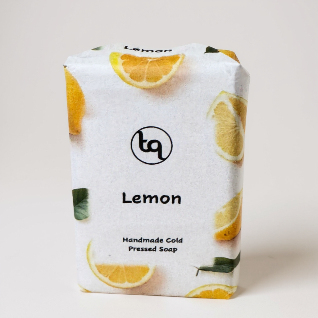 Truequest lemon cold‑pressed soap wrapped in white paper decorated with bright citrus slices and green leaves.