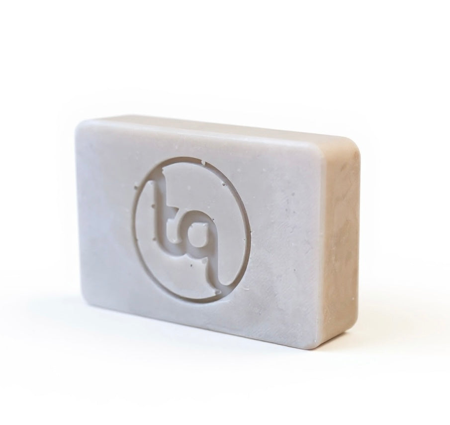 Light lilac Truequest soap bar with a circular tq emblem embossed on the front surface.