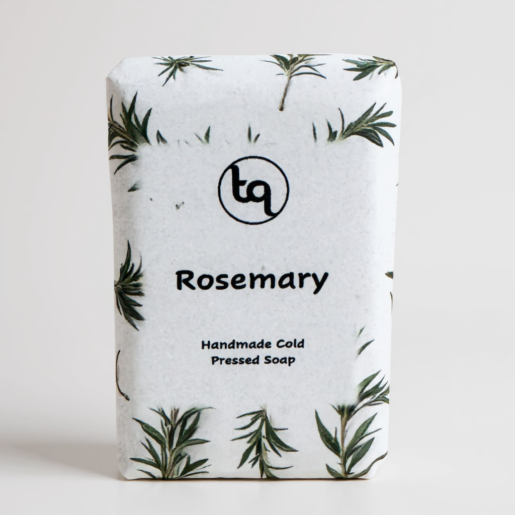 Handmade cold‑pressed rosemary soap wrapped in white paper with small green sprigs from TrueQuest Soap.