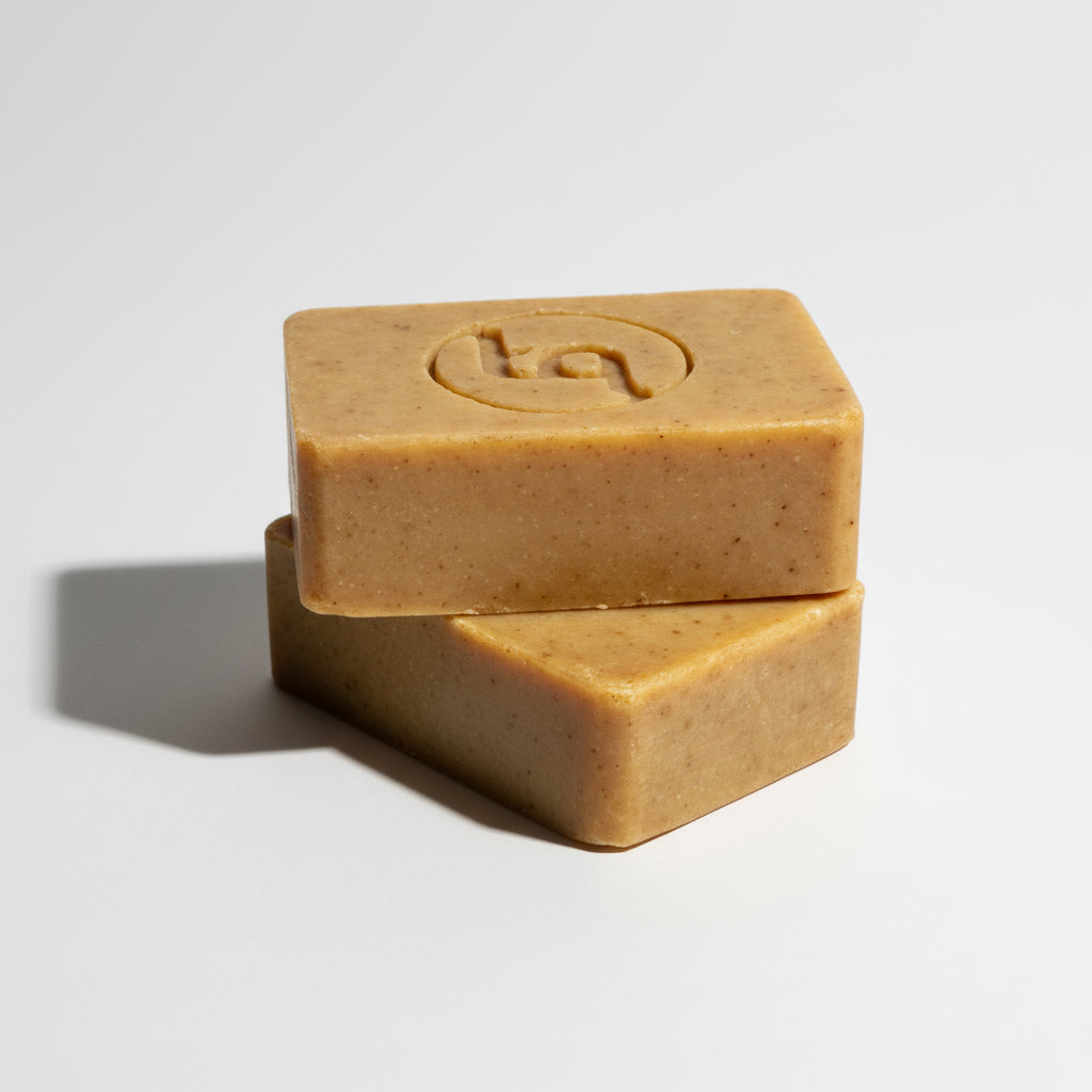 Two stacked bars of turmeric soap on a light gray background