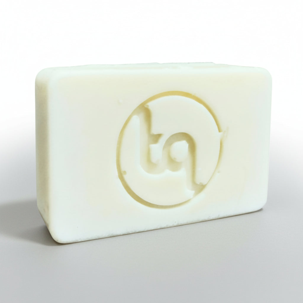 Plain natural bar of soap with Truequest logo on a light gray background