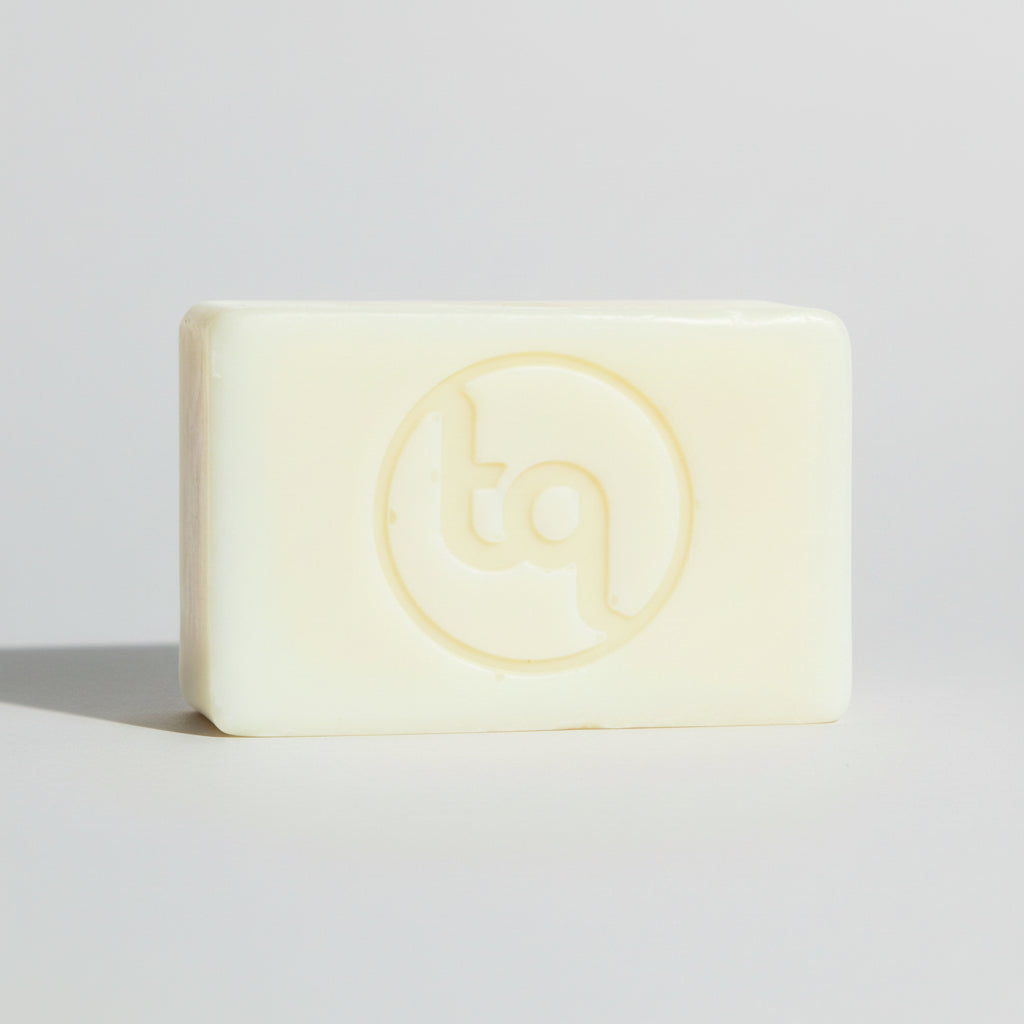 Bar of plain unfragranced and uncoloured natural soap with Truequest logo on a light gray background